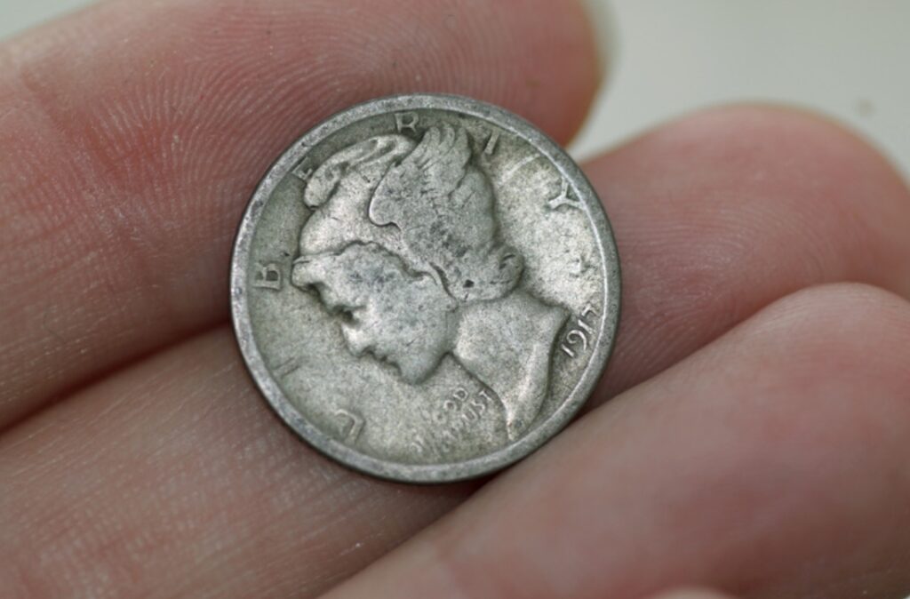 The front of a "Mercury" dime heled in a hand. This is used in money magic.